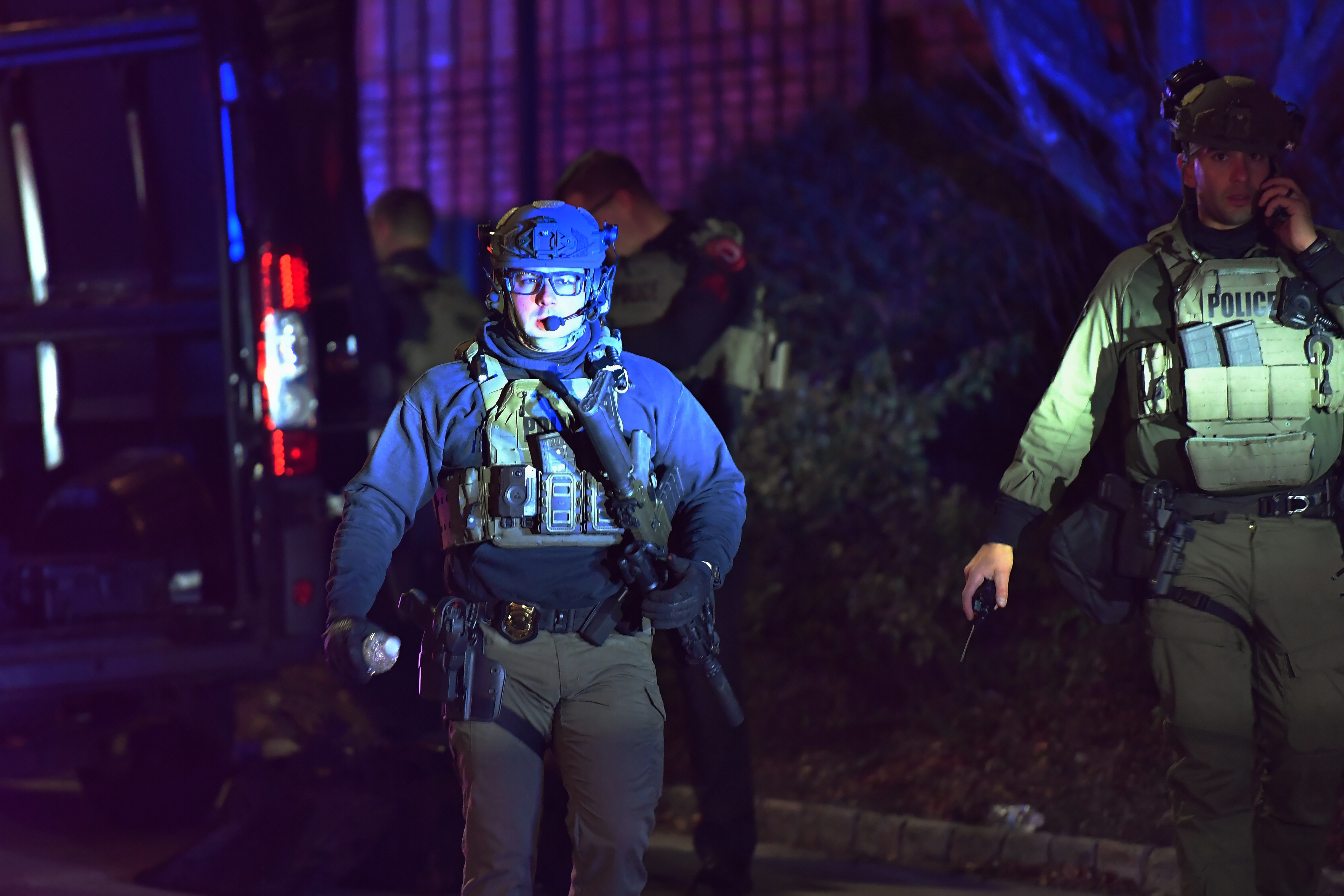 A law enforcement official carries a rifle in a neighborhood near Brown University, Saturday, Dec. 13, 2025, in Providence, R.I. during the investigation of a shooting. (AP Photo/Steven Senne)