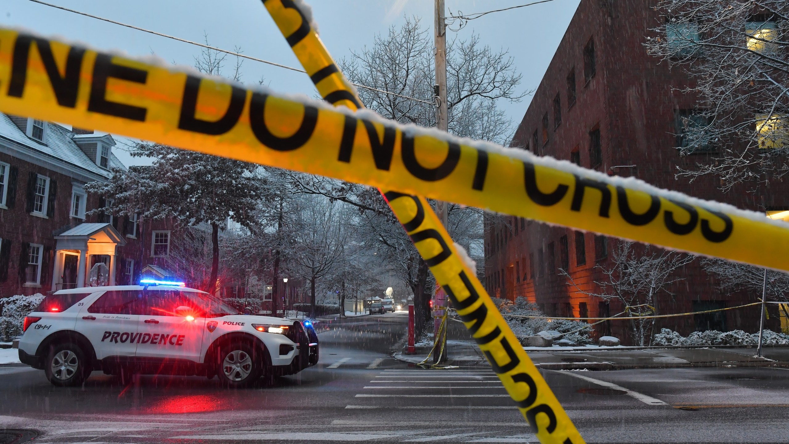 A police vehicle is parked at an intersection near crime scene tape at Brown University, Sunday, Dec. 14, 2025, in Providence, R.I., following a Saturday shooting at the university. (AP Photo/Steven Senne)
