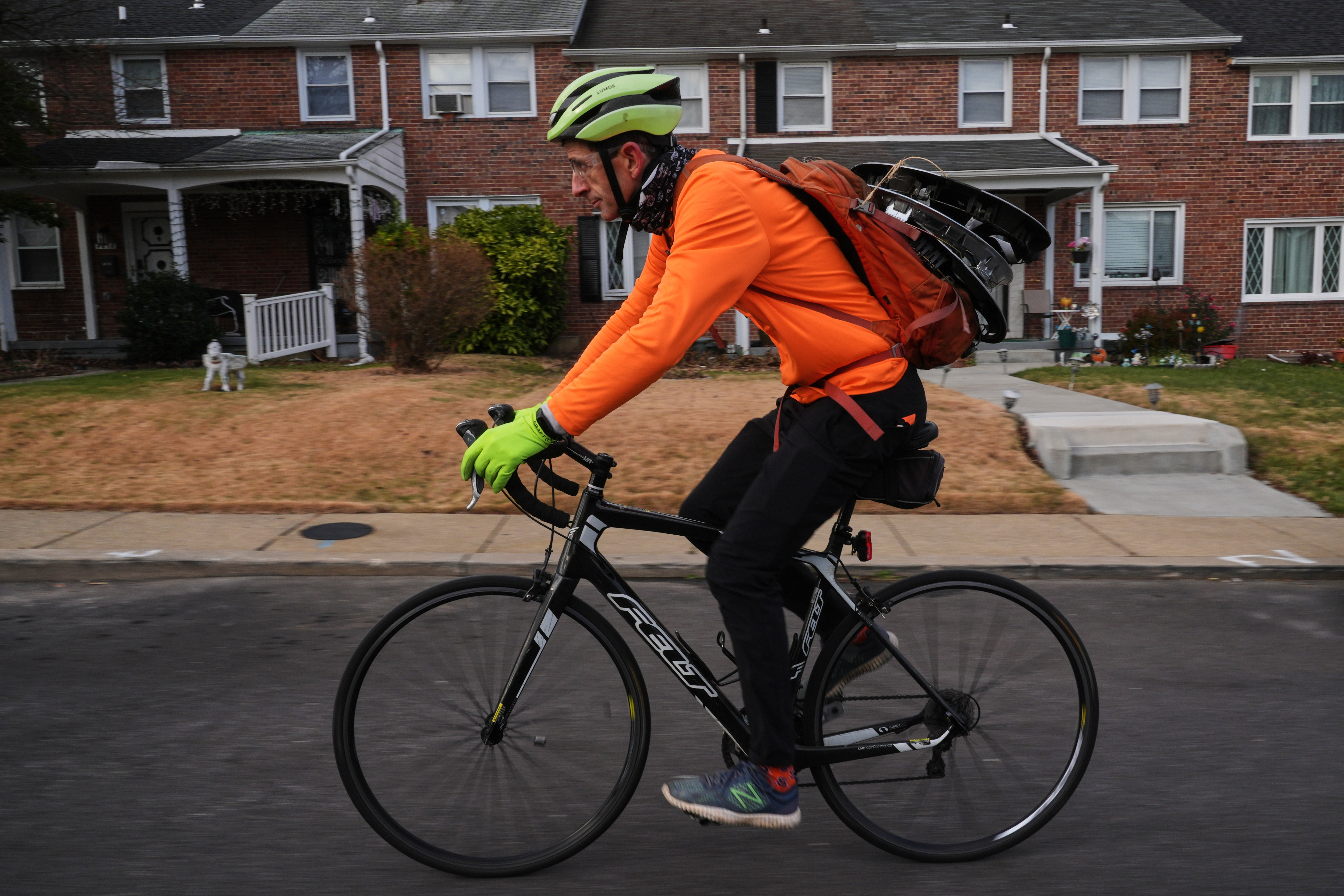 With hubcaps fastened to his backpack, cyclist Barnaby Wickham pedals through a neighborhood on his journey home, Thursday, Dec. 11, 2025, in Baltimore. (AP Photo/Stephanie Scarbrough)