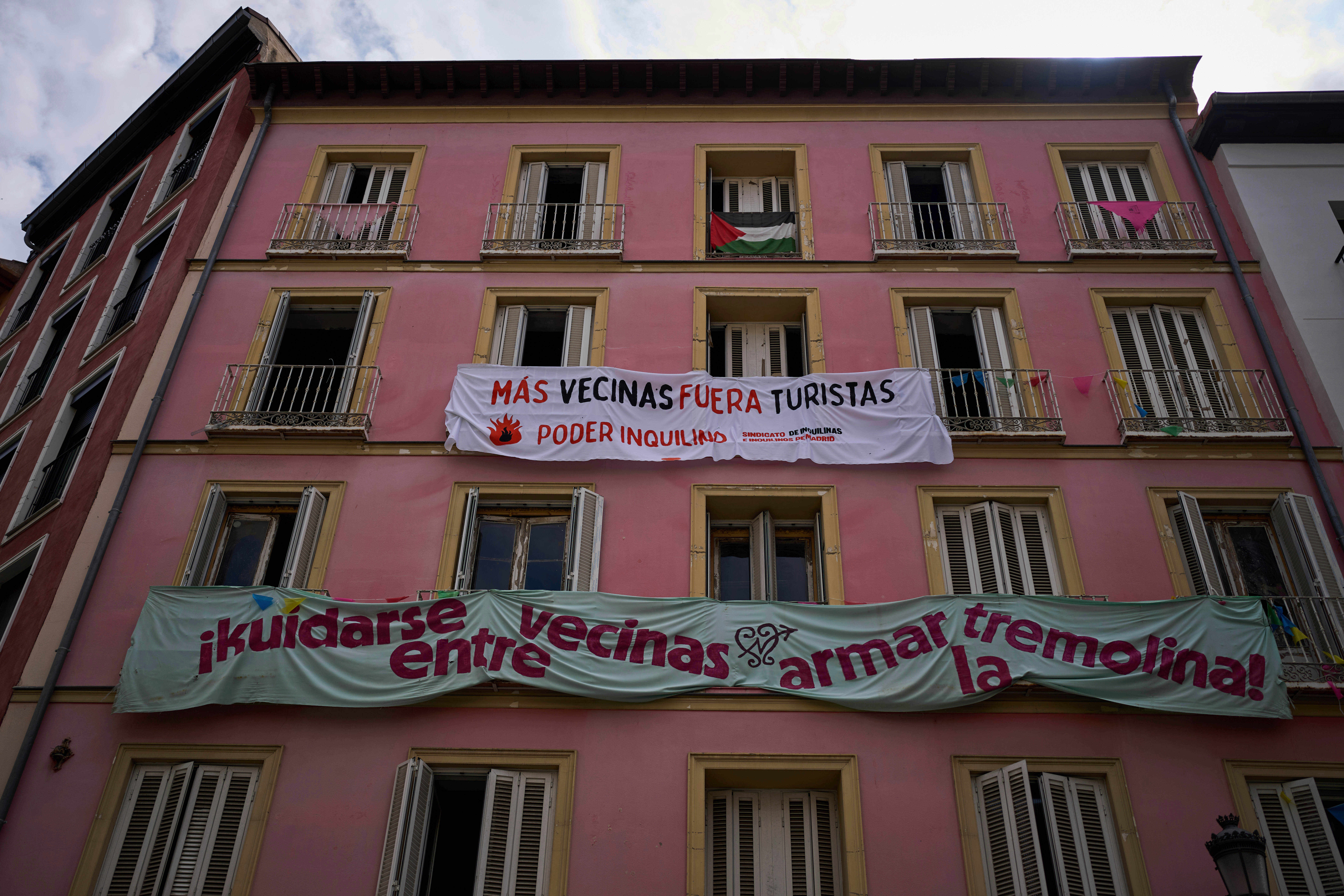 FILE - Banners against tourist holiday rentals hang on the facade of a building in downtown Madrid, Spain, Tuesday, June 3, 2025. The writing in Spanish reads: "More neighbors, fewer tourists. Tenant power," and "Looking out for each other as neighbors, stirring things up." (AP Photo/Manu Fernandez)