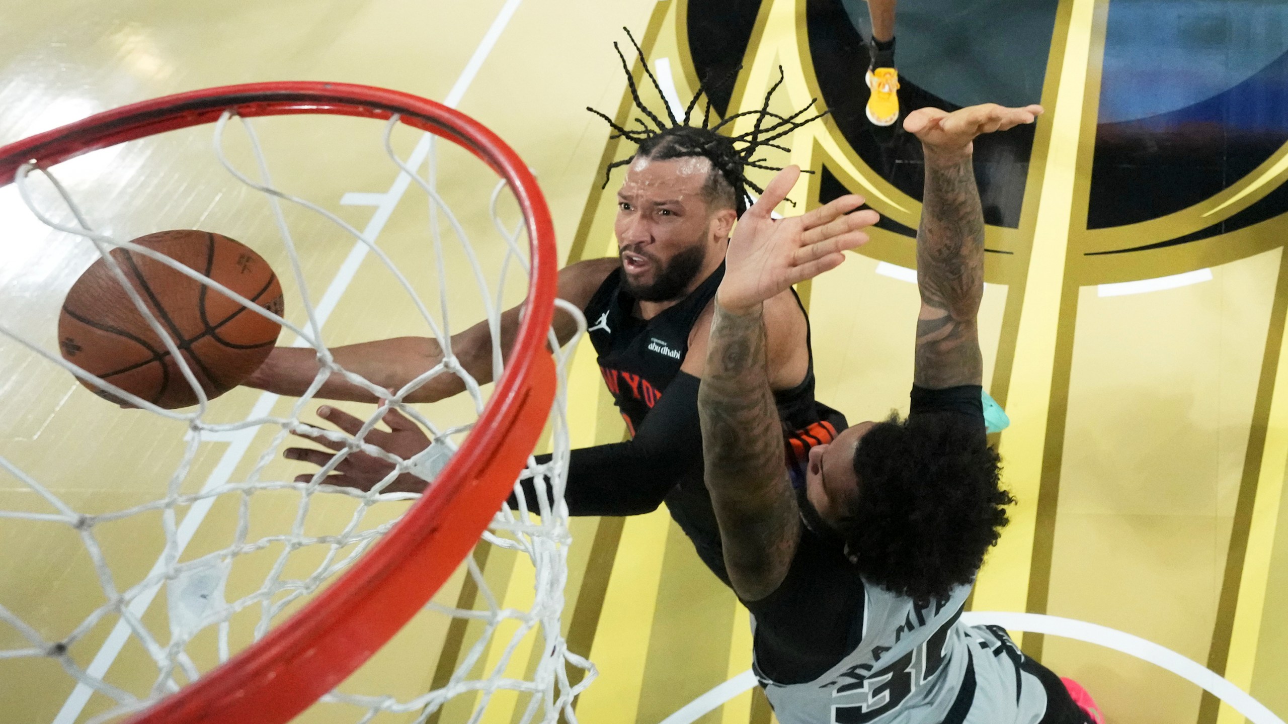 New York Knicks guard Jalen Brunson, left, shoots the ball past San Antonio Spurs forward Julian Champagnie (30) during an NBA Cup championship basketball game, Tuesday, Dec. 16, 2025, in Las Vegas. (Kirby Lee/Pool Photo via AP)