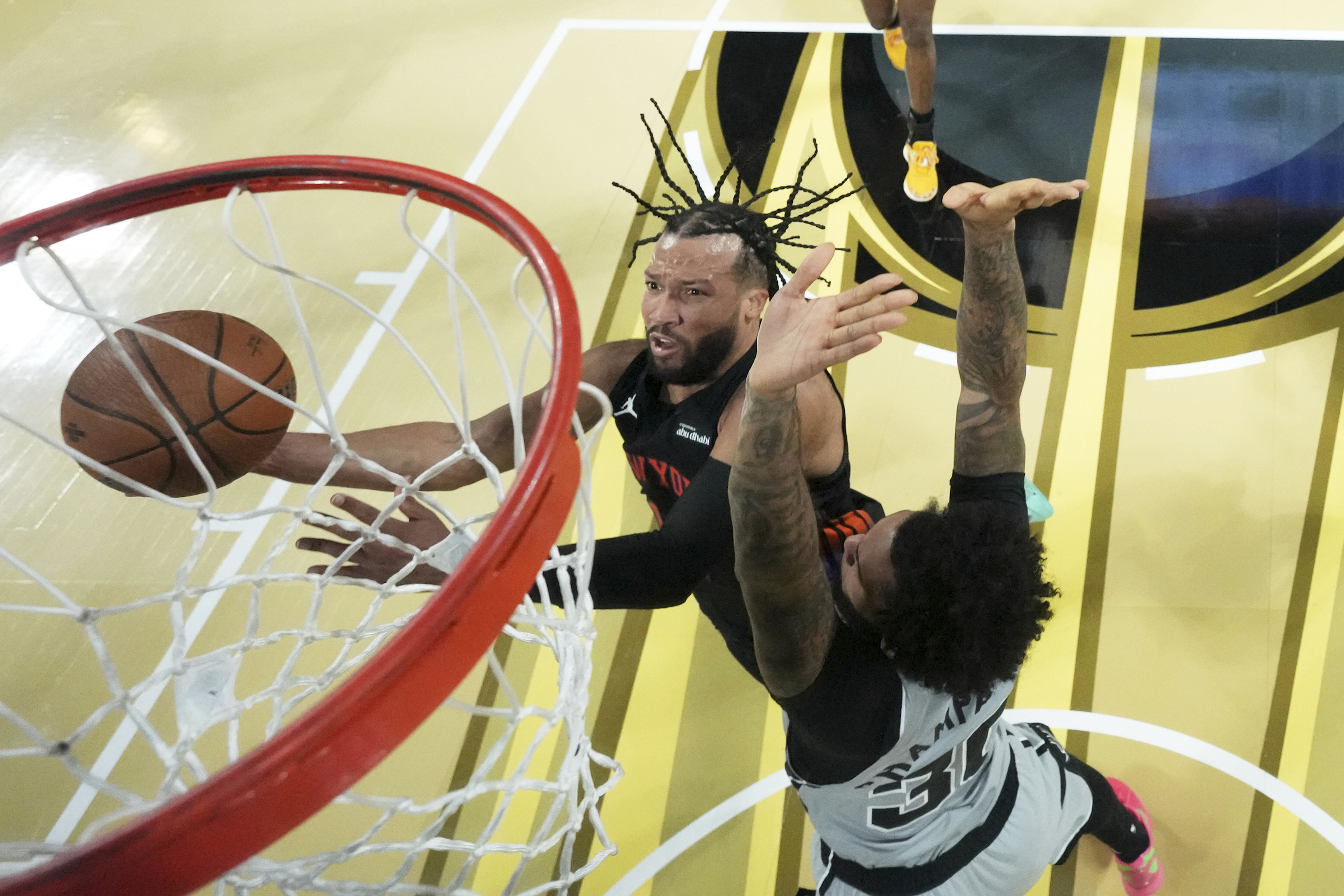 New York Knicks guard Jalen Brunson, left, shoots the ball past San Antonio Spurs forward Julian Champagnie (30) during an NBA Cup championship basketball game, Tuesday, Dec. 16, 2025, in Las Vegas. (Kirby Lee/Pool Photo via AP)