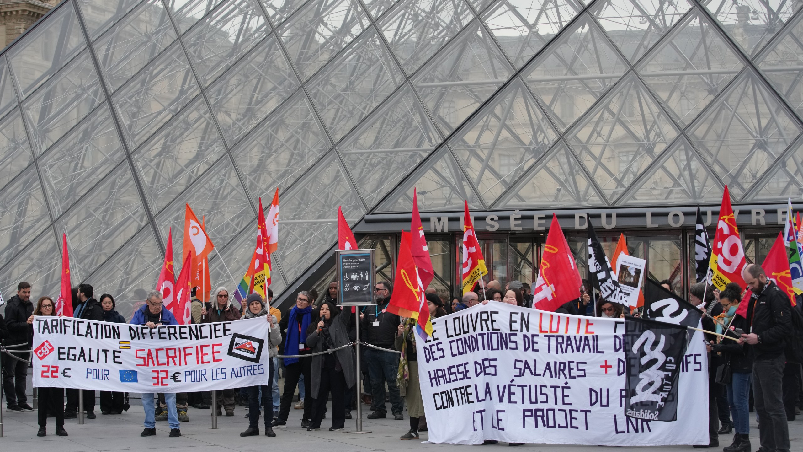 Unionists display a banner and union flags outside the Louvre museum after employees have voted to extend a strike that has disrupted operations at the world's most visited museum, Wednesday, Dec. 17, 2025 in Paris. (AP Photo/Christophe Ena)