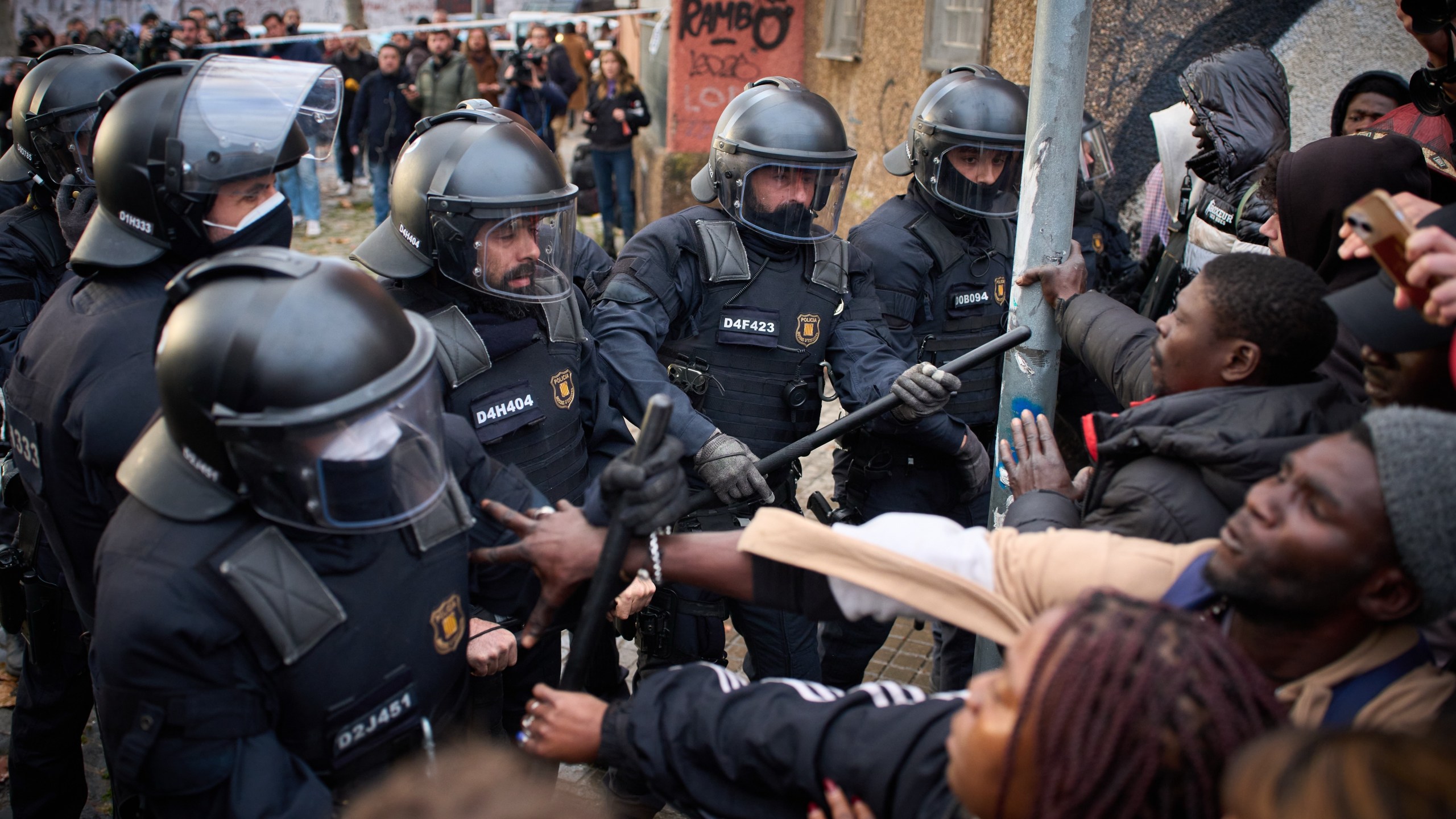 Migrants confront police as they begin carrying out eviction orders at an abandoned school building where hundreds of mostly undocumented migrants had been living, in Badalona, near Barcelona, Spain, Wednesday, Dec. 17, 2025. (AP Photo/Emilio Morenatti)